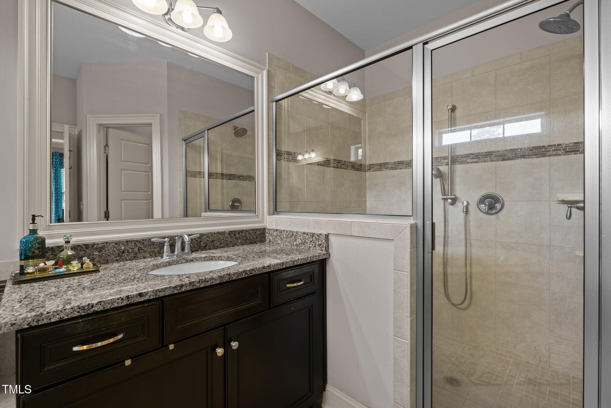 12216 Kyle Abbey Lane Raleigh, NC 27613 - Photo 25 of 60 a bathroom with a granite countertop shower sink and mirror