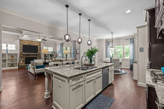 a kitchen with stainless steel appliances granite countertop a stove a refrigerator a kitchen island a dining table and chairs with wooden floor