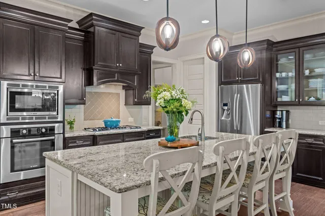 a kitchen with stainless steel appliances granite countertop a sink a stove and chairs