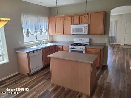 a kitchen with stainless steel appliances granite countertop a stove a sink dishwasher and a refrigerator with wooden floor