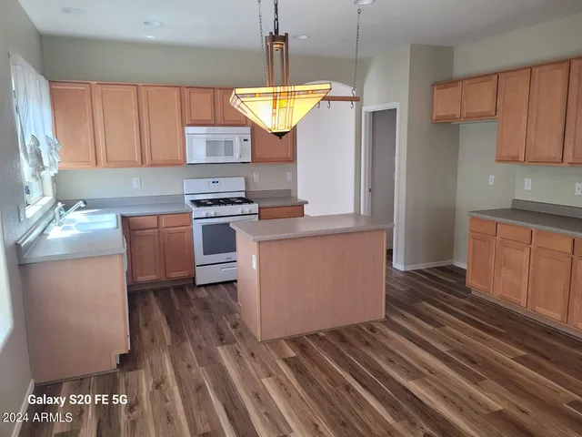 a kitchen with kitchen island granite countertop a sink cabinets and stainless steel appliances