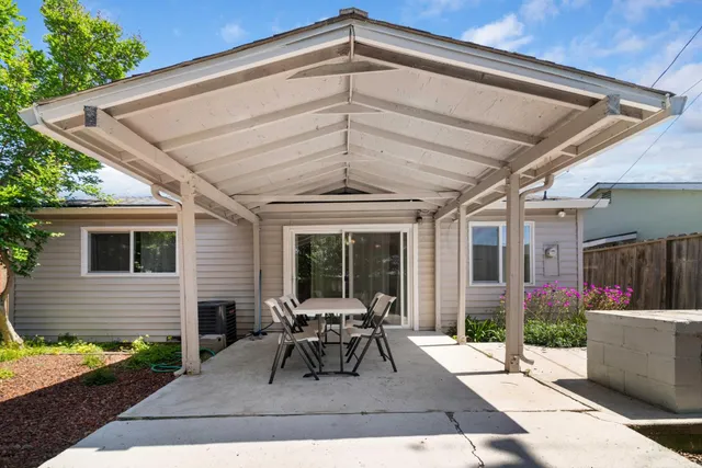 a view of a patio with table and chairs potted plants with floor to ceiling window and potted plants