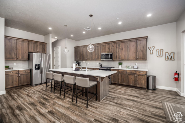 2600 Ocotillo Way, Unit 34 Santa Clara, UT 84765 - Photo 2 of 43 Kitchen with a kitchen breakfast bar, appliances with stainless steel finishes, decorative backsplash, hanging light fixtures, and an island with sink