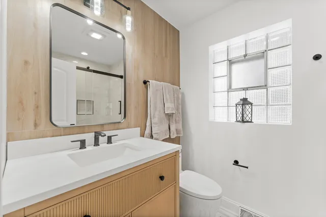 a bathroom with a sink toilet vanity and shower