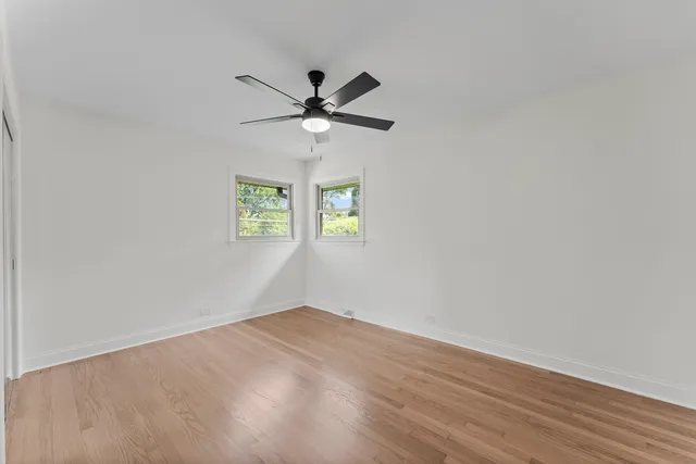 an empty room with windows and fan