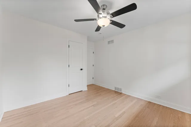 an empty room with a ceiling fan and wooden floor