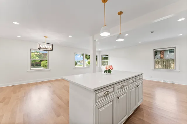 a kitchen with kitchen island a sink dishwasher a stove and a dining table with wooden floor