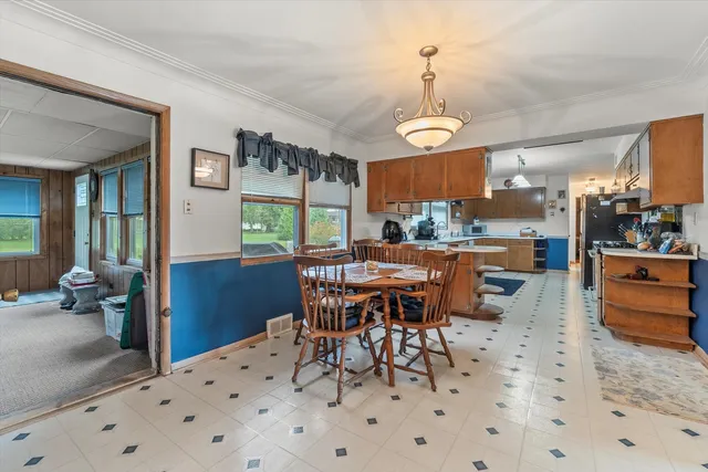 a view of a dining room and livingroom with furniture wooden floor a rug a painting and a chandelier