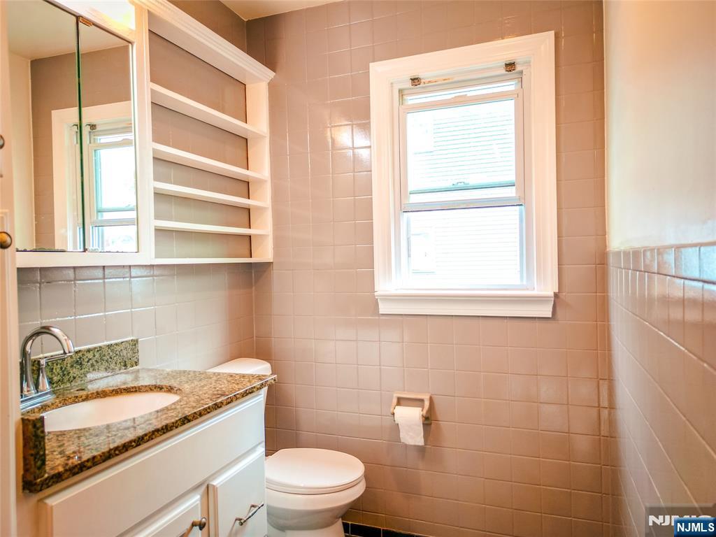 104 Eastern Way Rutherford, NJ 07070 - Photo 5 of 16 a bathroom with a granite countertop toilet a sink and a window