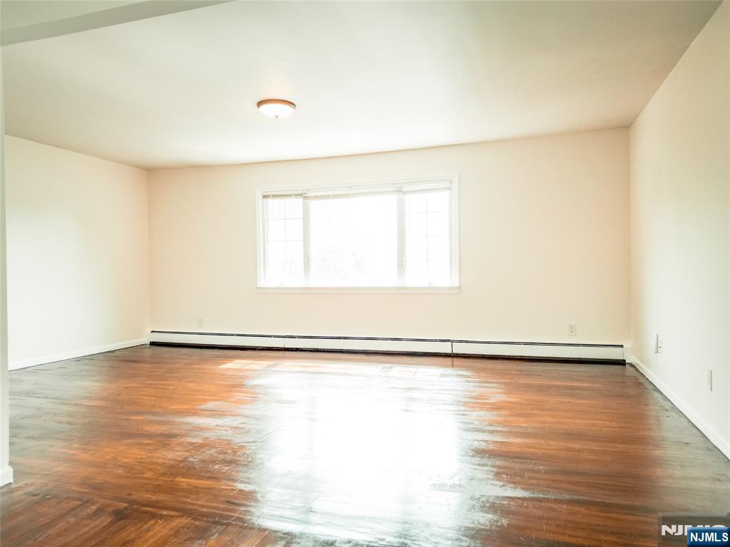 104 Eastern Way Rutherford, NJ 07070 - Photo 7 of 16 a view of an empty room with wooden floor and a window