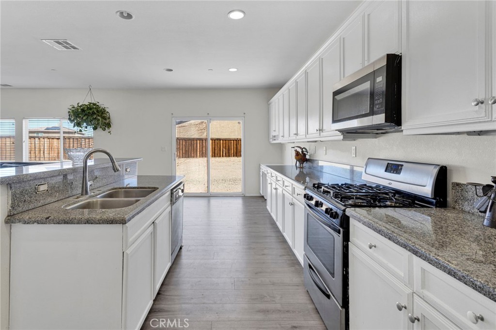 14245 Purple Canyon Road Adelanto, CA 92301 - Photo 15 of 38 a kitchen with stainless steel appliances granite countertop a sink stove and microwave