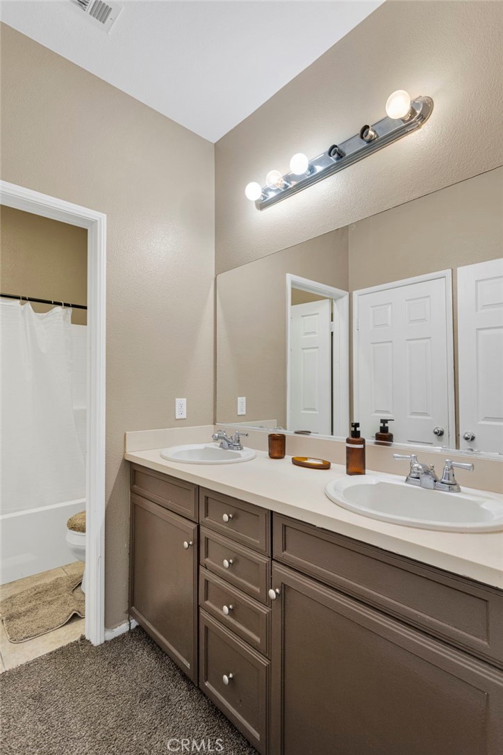 14245 Purple Canyon Road Adelanto, CA 92301 - Photo 20 of 38 a bathroom with a double vanity sink and a mirror