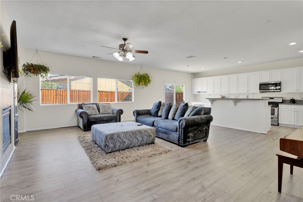14245 Purple Canyon Road Adelanto, CA 92301 - Photo 6 of 38 a living room with furniture a ceiling fan a flat screen tv and a window