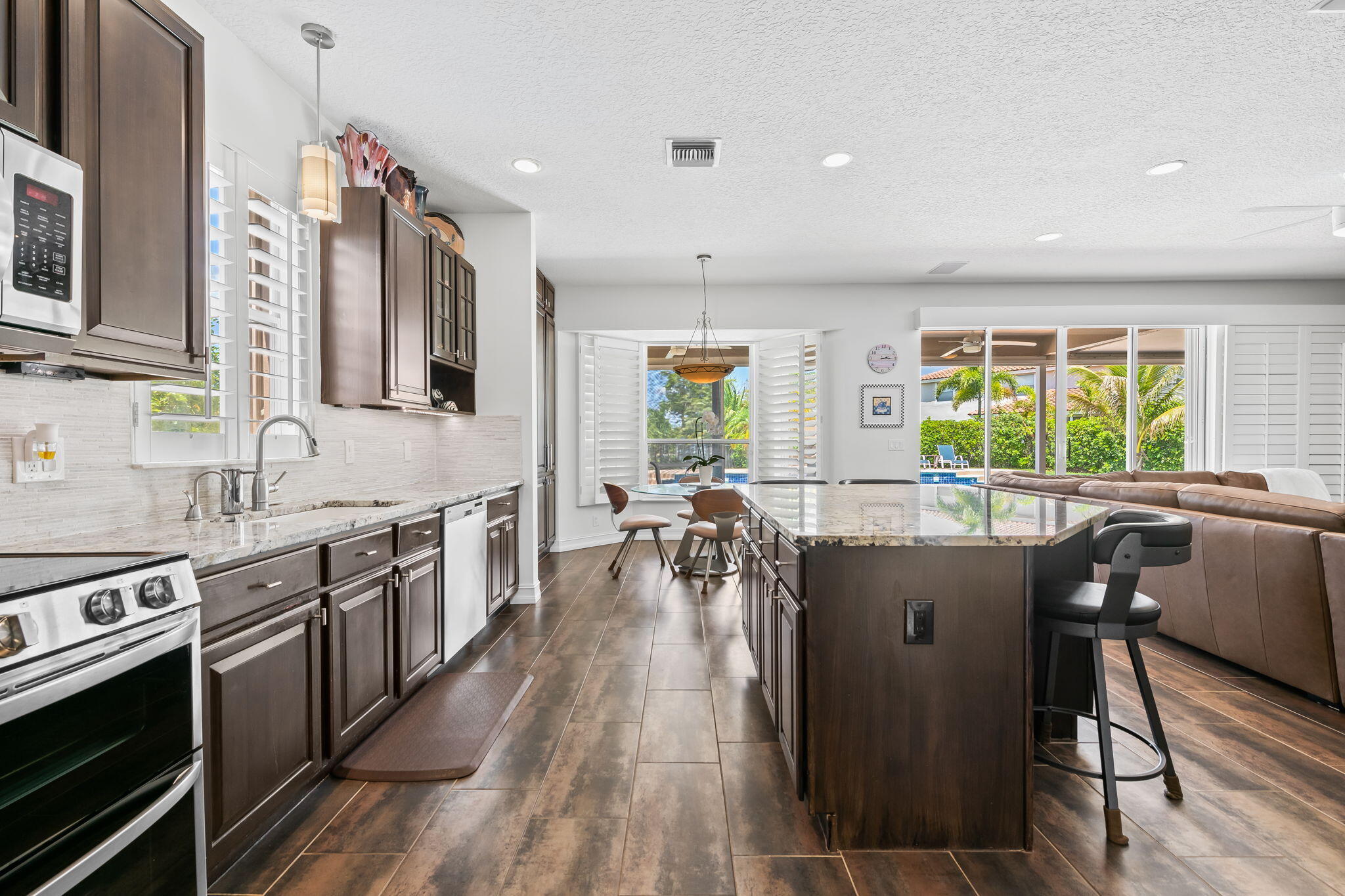 12781 Yardley Drive Boca Raton, FL 33428 - Photo 9 of 55 a kitchen with stainless steel appliances granite countertop a stove top oven a sink dishwasher a dining table and chairs with wooden floor