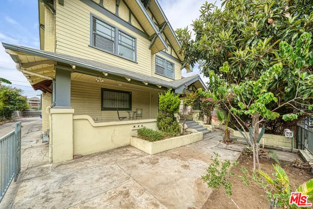 a view of a white house with a large tree