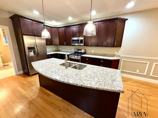 a kitchen with stainless steel appliances granite countertop a sink a stove and a refrigerator