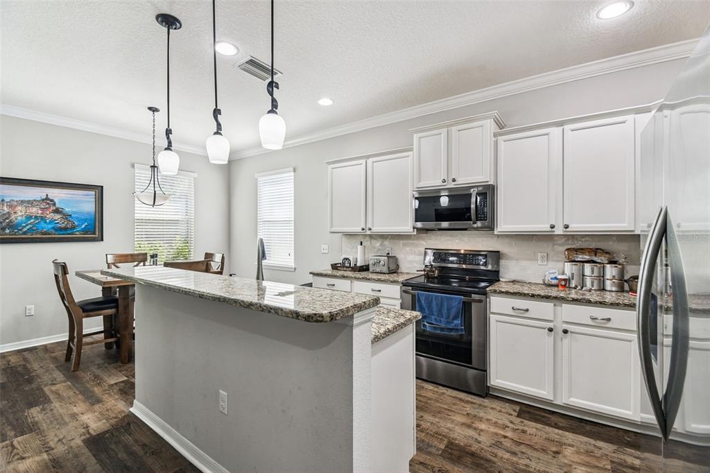 11150 Paradise Pointe Way New Port Richey, FL 34654 - Photo 19 of 91 a kitchen with stainless steel appliances granite countertop a sink a stove a microwave a center island and cabinets