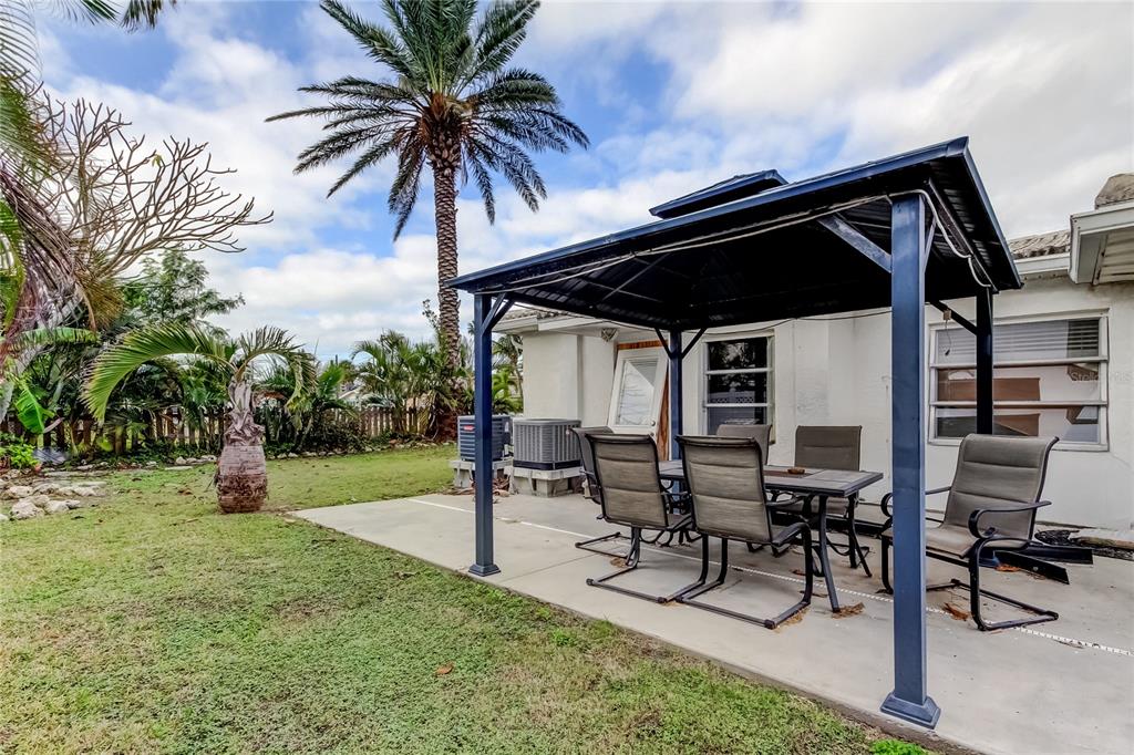 245 145th Avenue Madeira Beach, FL 33708 - Photo 19 of 41 a view of patio with table and chairs and potted plants with wooden fence