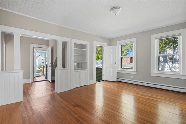 an empty room with wooden floor and windows