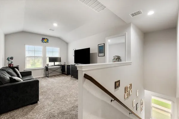 a view of a hallway with a livingroom and a chandelier fan wooden floor and windows