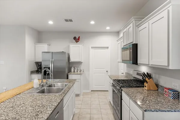 a kitchen with granite countertop a sink stove and refrigerator