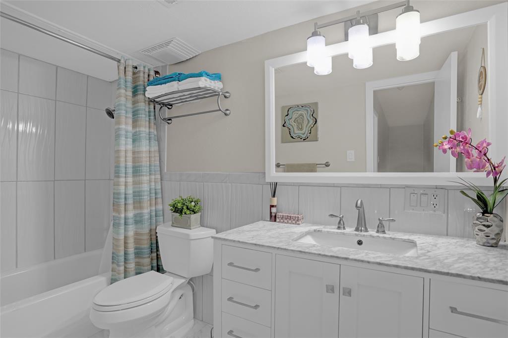 12834 Midway Road, Unit 2110 Dallas, TX 75244 - Photo 16 of 22 Full bathroom with vanity, a wainscoted wall, and shower / tub combo