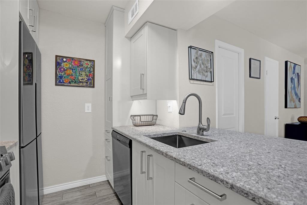 12834 Midway Road, Unit 2110 Dallas, TX 75244 - Photo 5 of 22 Kitchen with white cabinets, light stone counters, stainless steel appliances, and light wood finished floors