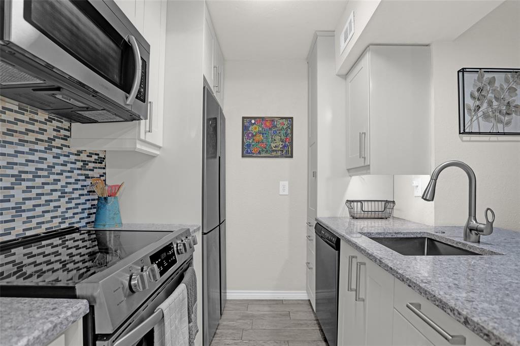 12834 Midway Road, Unit 2110 Dallas, TX 75244 - Photo 6 of 22 Kitchen with stainless steel appliances, light stone countertops, white cabinetry, wood finish floors, and decorative backsplash