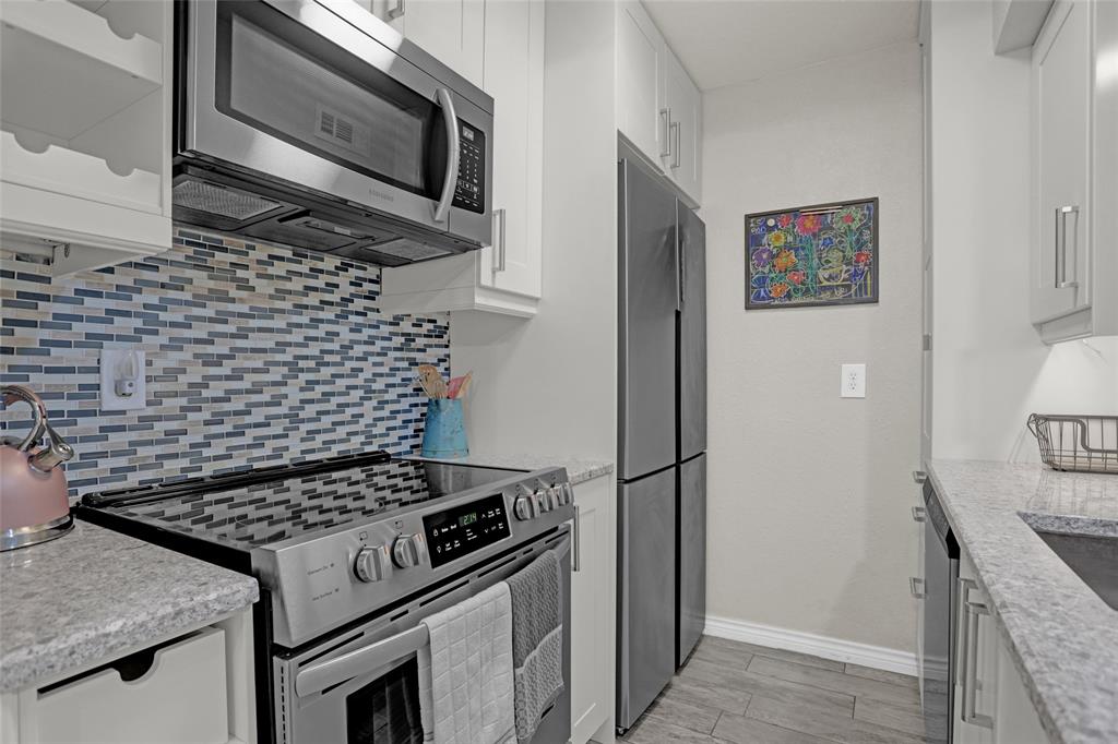 12834 Midway Road, Unit 2110 Dallas, TX 75244 - Photo 7 of 22 Kitchen with stainless steel appliances, decorative backsplash, light stone counters, and white cabinets