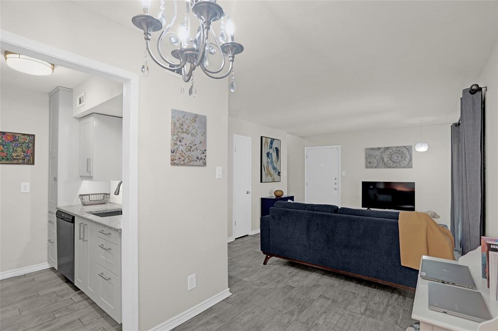 12834 Midway Road, Unit 2110 Dallas, TX 75244 - Photo 22 of 22 Kitchen with light wood finished floors, white cabinets, suspended lighting, open floor plan, and stainless steel dishwasher
