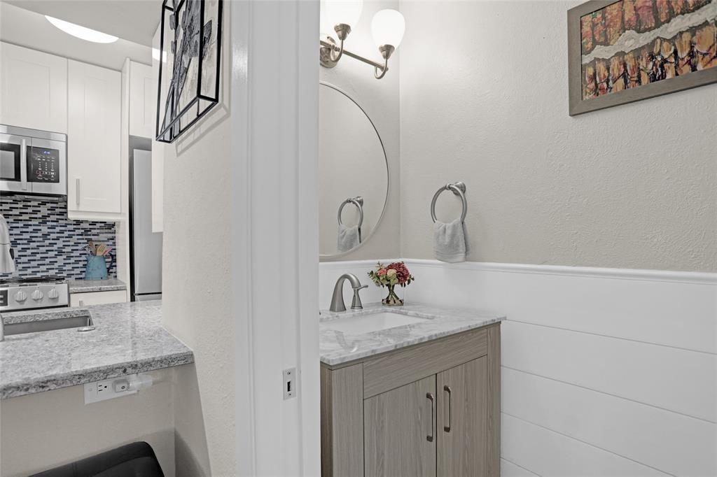 12834 Midway Road, Unit 2110 Dallas, TX 75244 - Photo 8 of 22 Half bathroom with vanity, decorative backsplash, a textured wall, and a wainscoted wall