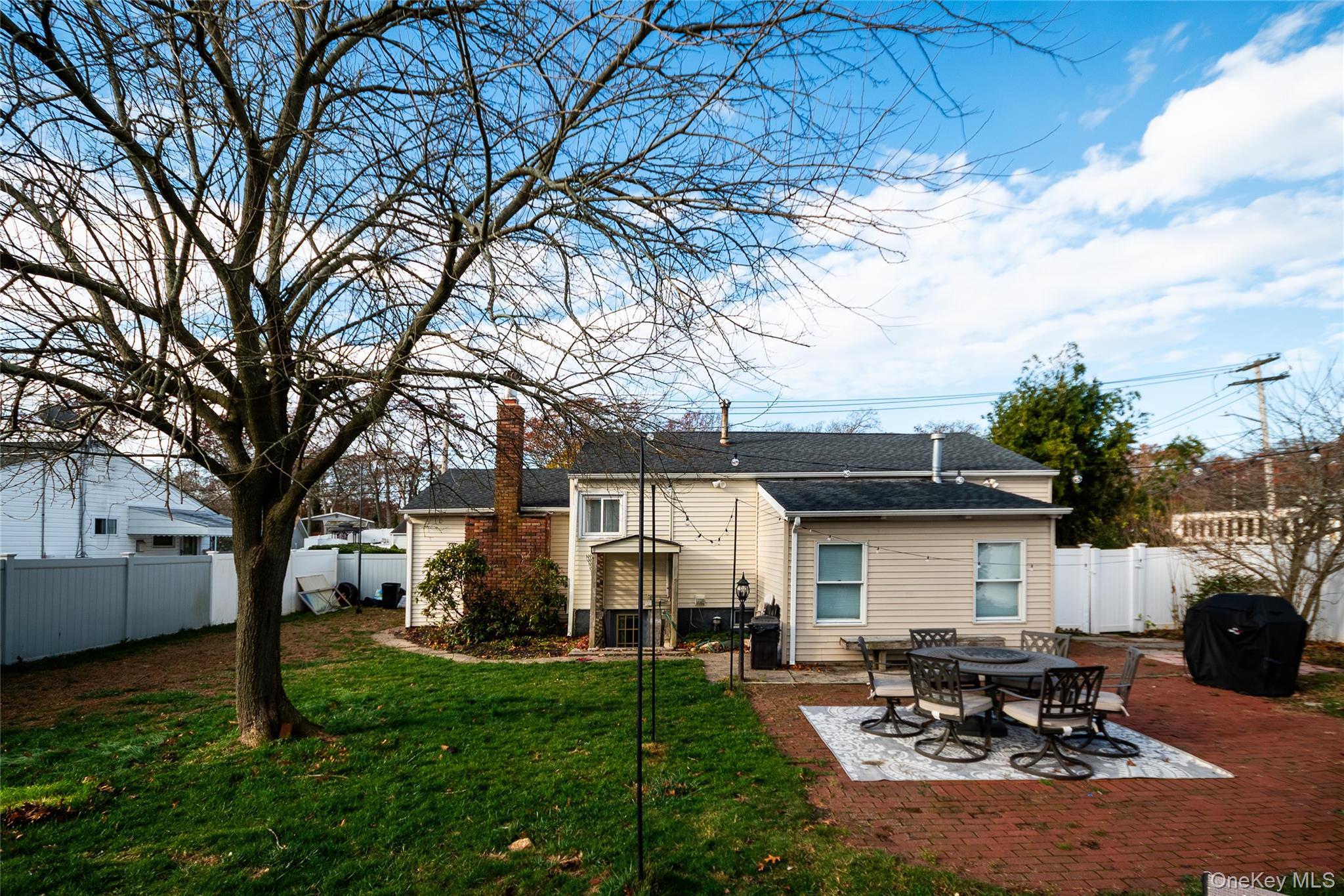 277 Horseblock Road Farmingville, NY 11738 - Photo 25 of 28 Back of property with a patio area, a fenced backyard, and a chimney