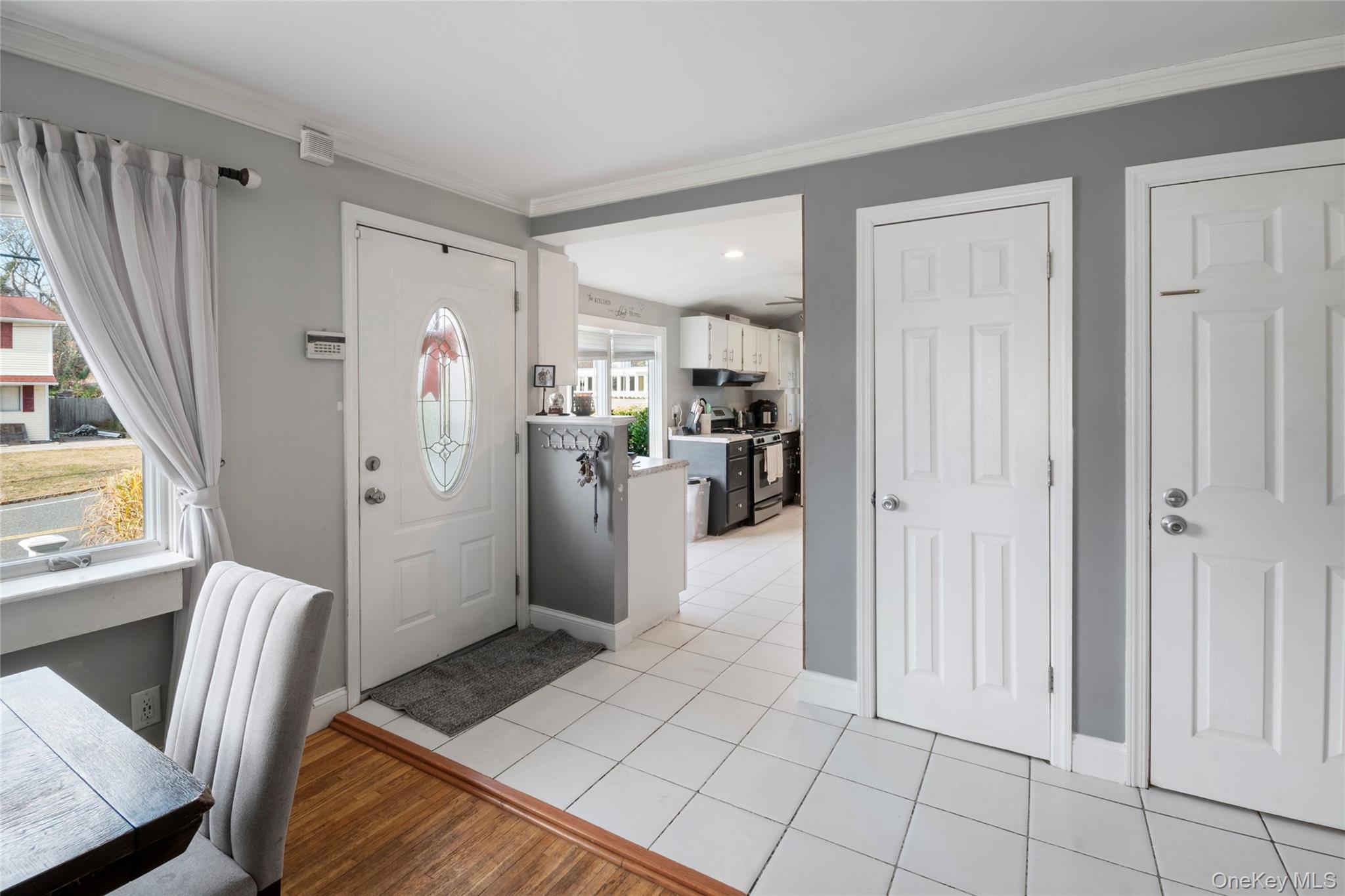 277 Horseblock Road Farmingville, NY 11738 - Photo 7 of 28 Entryway with light wood-style flooring and crown molding