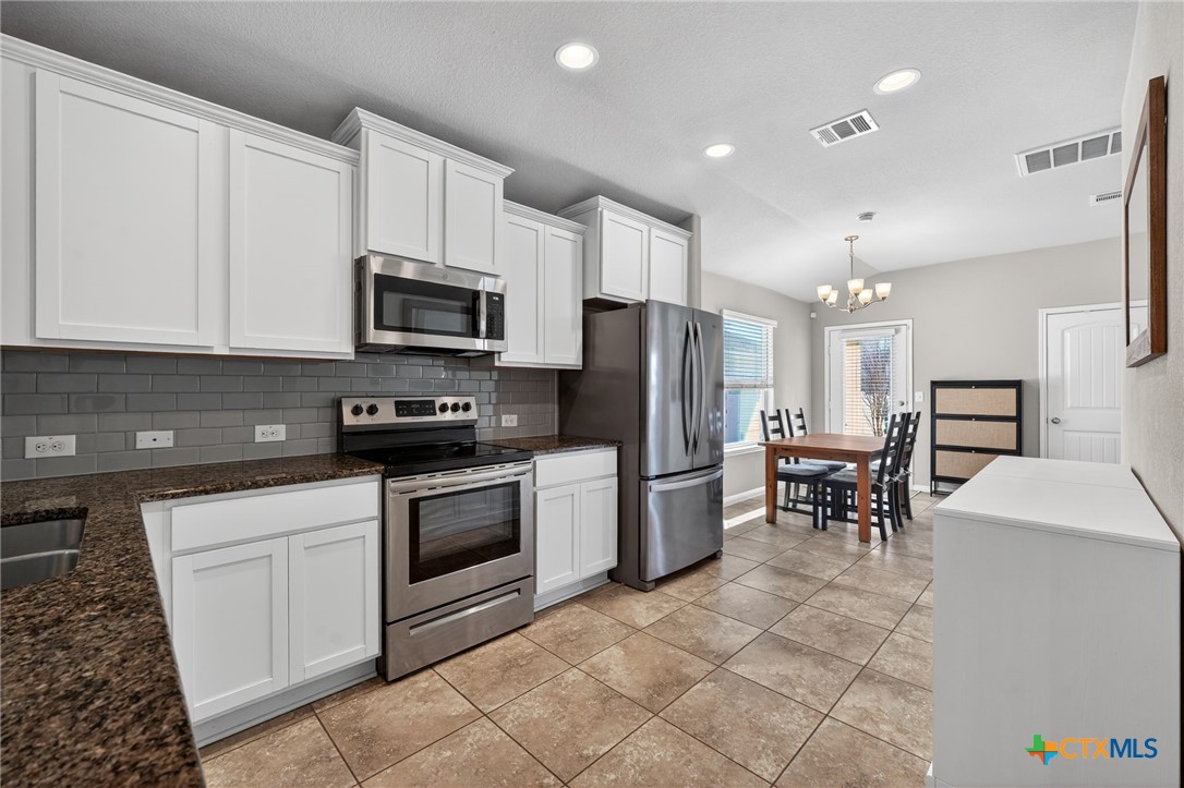 201 Cane River Road Pflugerville, TX 78660 - Photo 3 of 21 a kitchen with stainless steel appliances granite countertop a stove a sink a microwave a refrigerator and cabinets