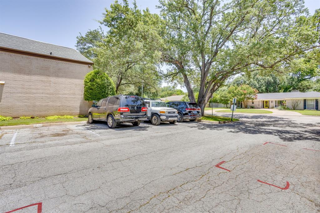 4102 Ridglea Country Club Drive, Unit 1503 Fort Worth, TX 76126 - Photo 21 of 21 Paved parking area featuring multiple designated parking spaces, surrounded by mature trees and landscaping