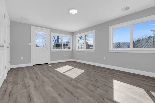 a view of an empty room with a window and wooden floor