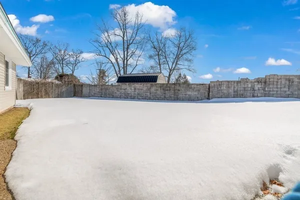 a view of a yard covered with snow in front of house