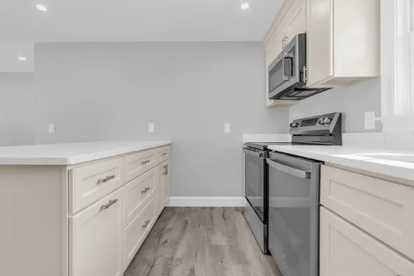 a kitchen with stainless steel appliances white cabinets and a wooden floor