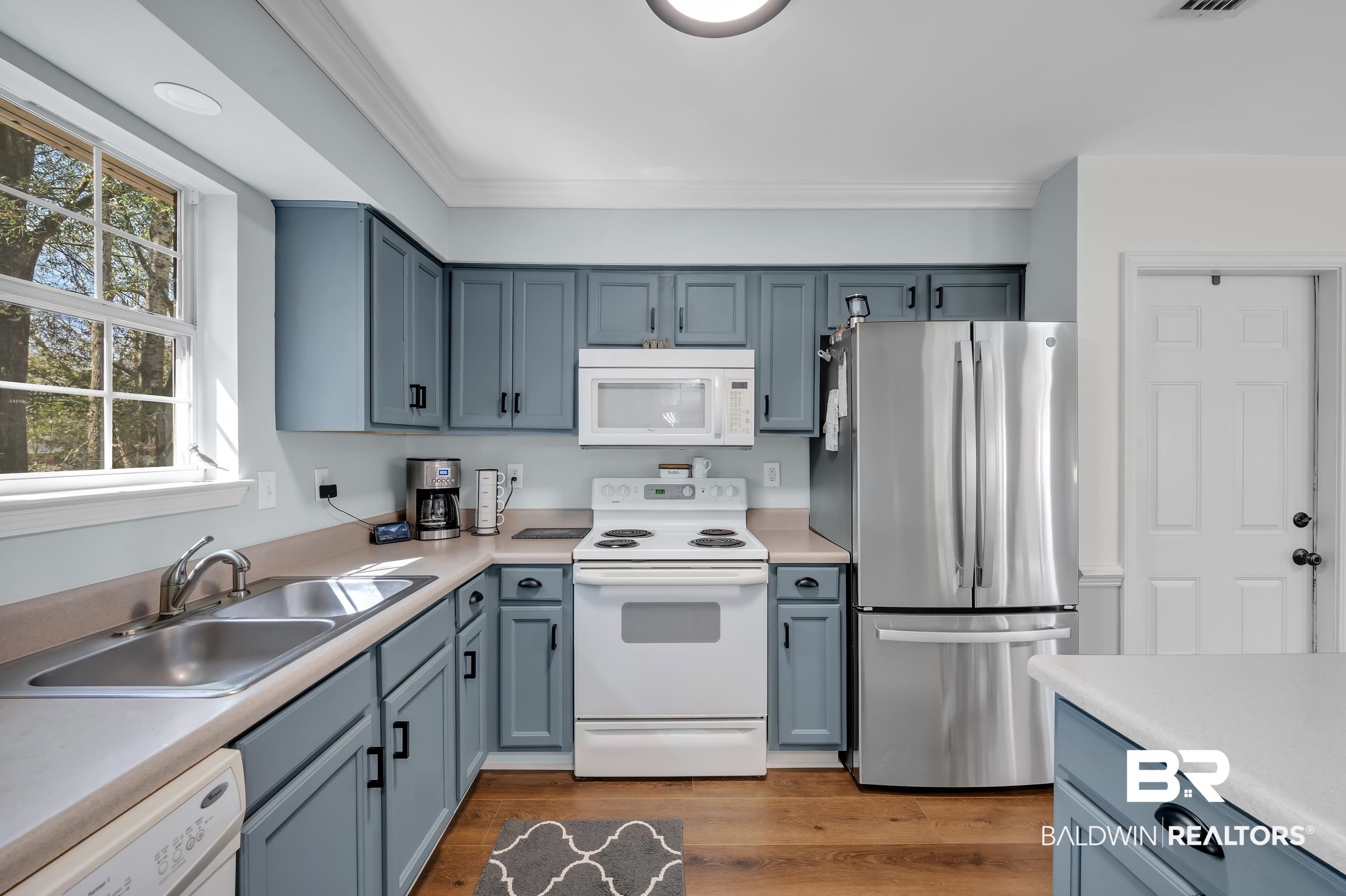 191 Robbins Boulevard Daphne, AL 36526 - Photo 9 of 24 Kitchen featuring white appliances, light countertops, light wood-style floors, blue cabinetry, and crown molding