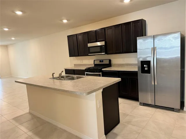 a kitchen with a sink a microwave a refrigerator and cabinets