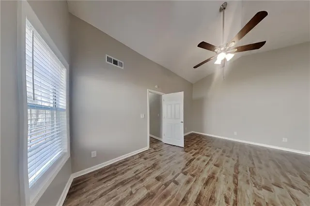 a view of an empty room with window and chandelier fan