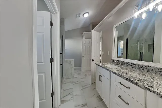 a spacious bathroom with a granite countertop sink mirror and shower