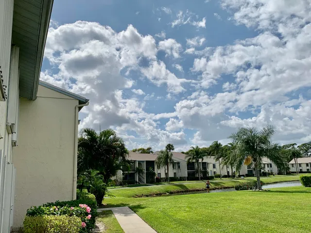 a view of a big house with a big yard and palm trees