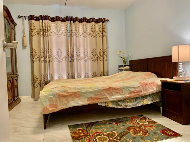 a bed sitting in a bedroom next to a curtain and a curtain