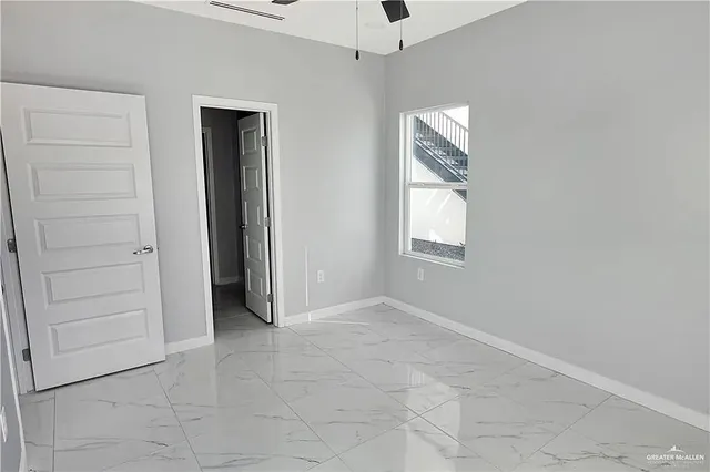 an empty room with a window and a fan