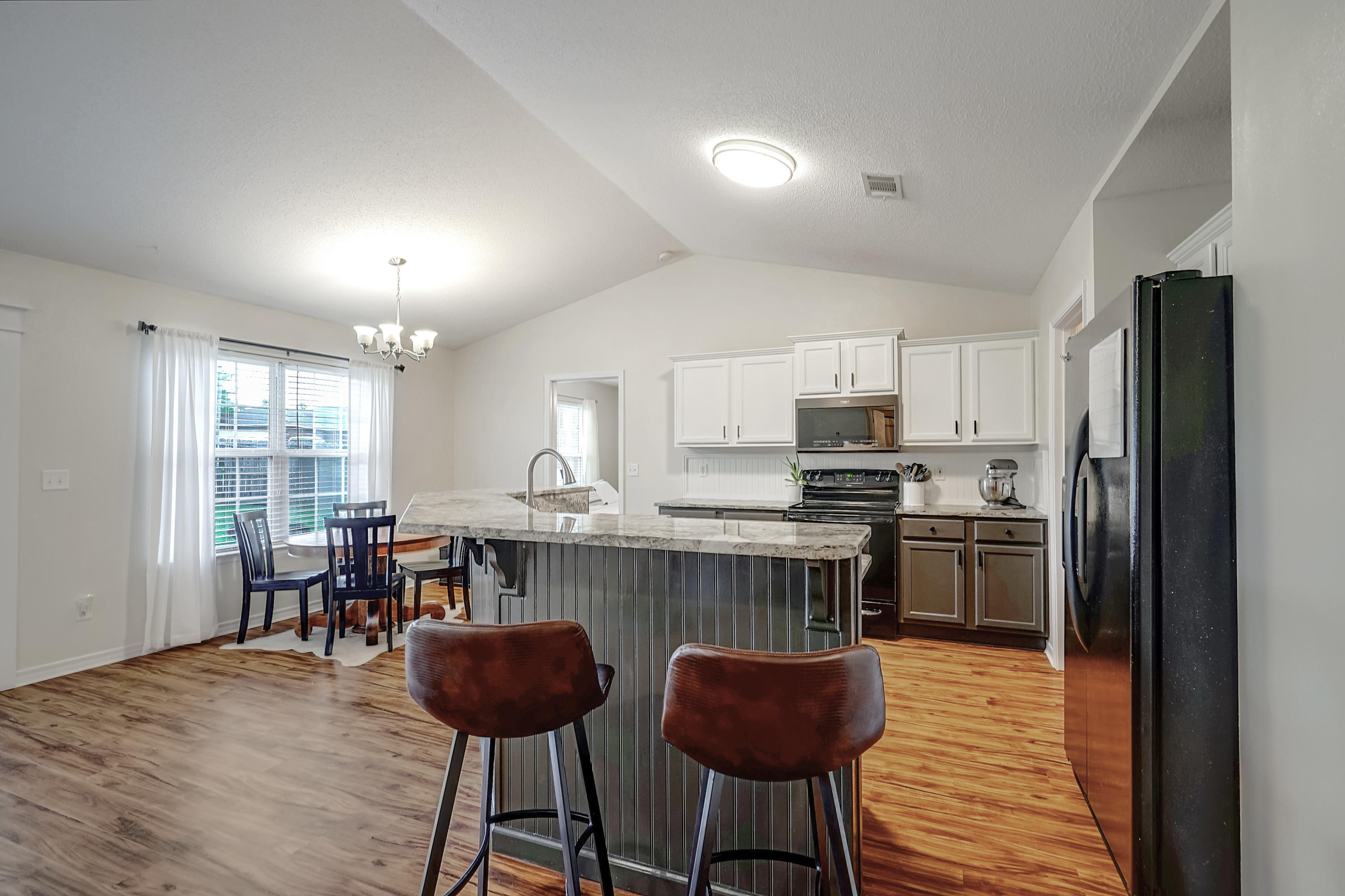 5145 Eagle Way Crestview, FL 32539 - Photo 6 of 15 a kitchen with stainless steel appliances granite countertop a stove refrigerator a dining table and chairs with wooden floor