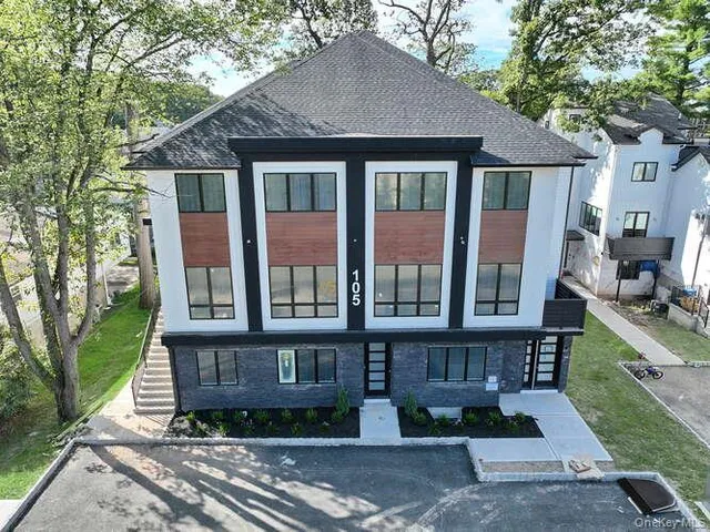 a view of a brick house with many windows plants and large tree
