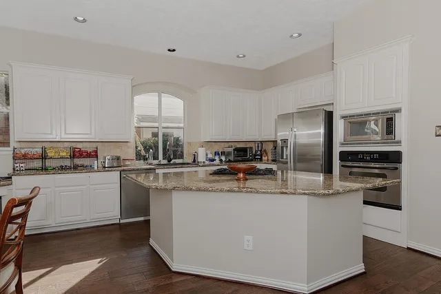 a kitchen with stainless steel appliances granite countertop a refrigerator a stove a sink and a refrigerator