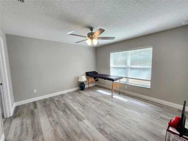 an empty room with windows and ceiling fan