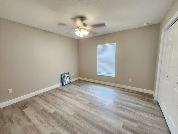 a view of an empty room with chandelier fan and wooden floor